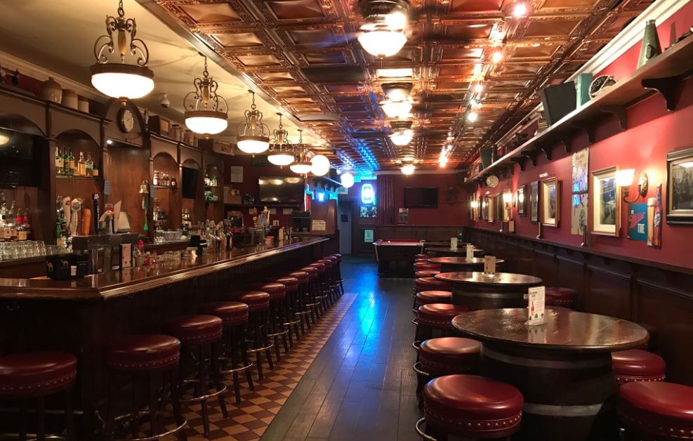 Exterior view of JJ Sullivan's Irish Pub featuring a welcoming entrance, traditional Irish decor, and outdoor seating under a canopy, with a vibrant atmosphere and greenery surrounding the area.