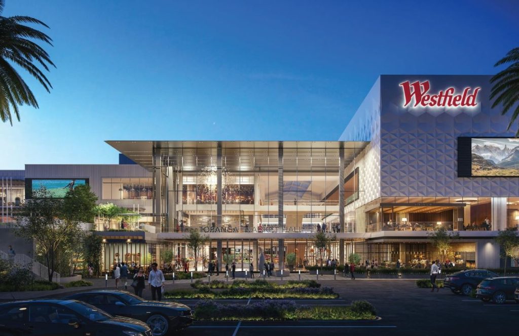 Aerial view of Westfield Topanga shopping center featuring a modern architectural design with multiple retail stores, outdoor spaces, and parking areas surrounded by greenery.