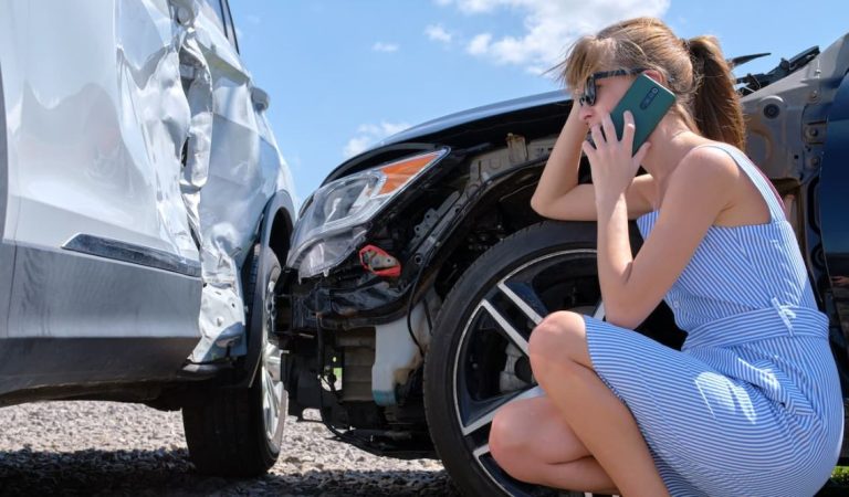 Car accident lawyer standing confidently with arms crossed, wearing a suit, in front of a blurred image of a car crash scene.