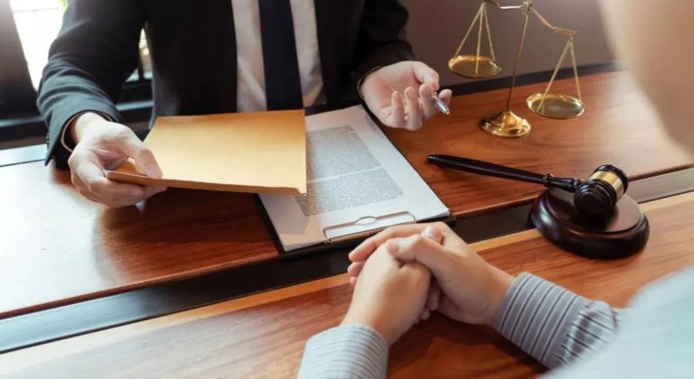 Personal injury attorney sitting at a desk with a laptop, reviewing documents and taking notes in an office setting.