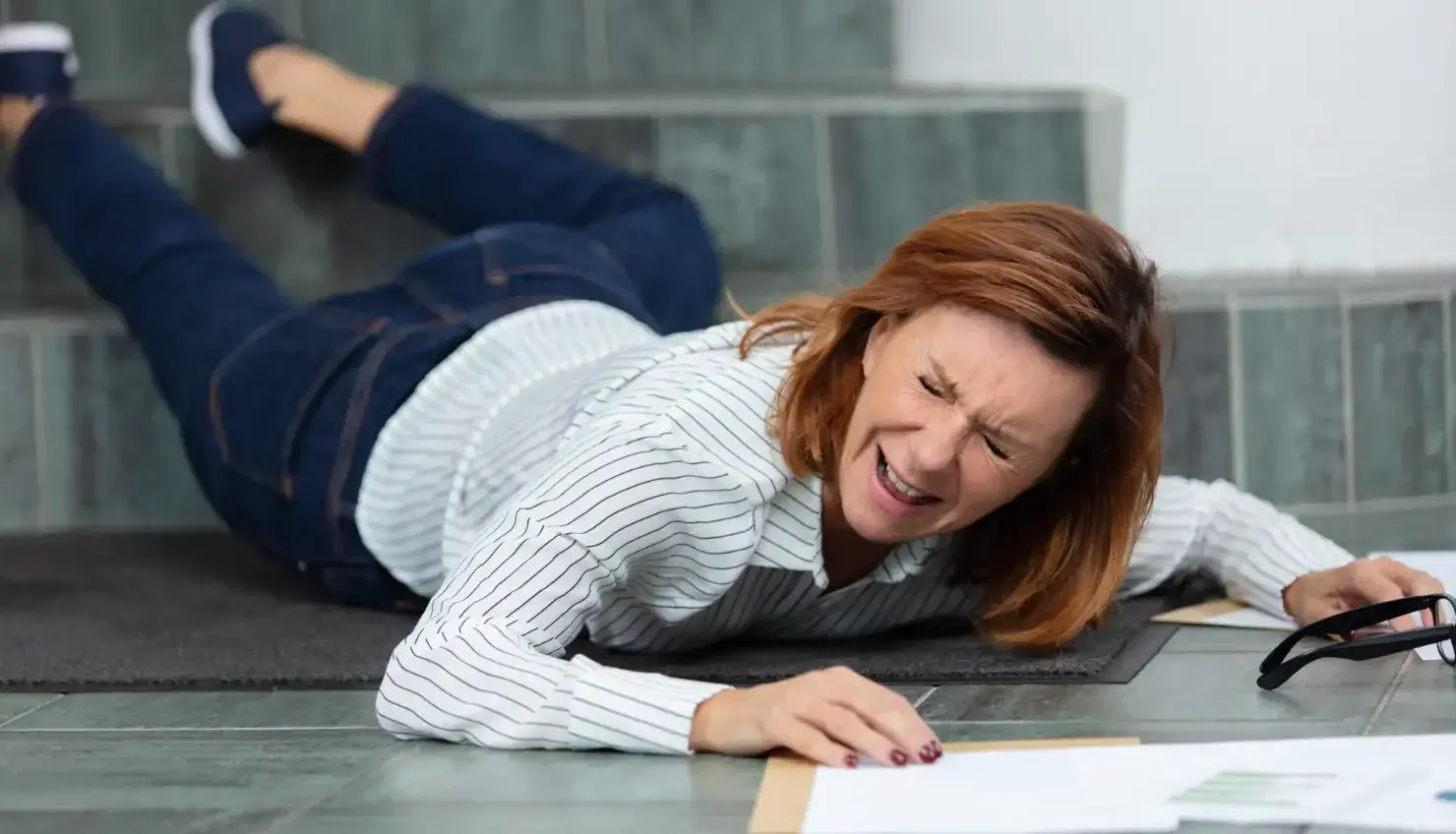 A concerned woman standing on a wet floor, looking down with a worried expression, symbolizing the risks of slip and fall accidents.